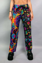 Model wearing Freedom Rave Wear pants featuring a vibrant mix of psychedelic patterns, including mushrooms and abstract designs. Perfect for rave and festival fashion.