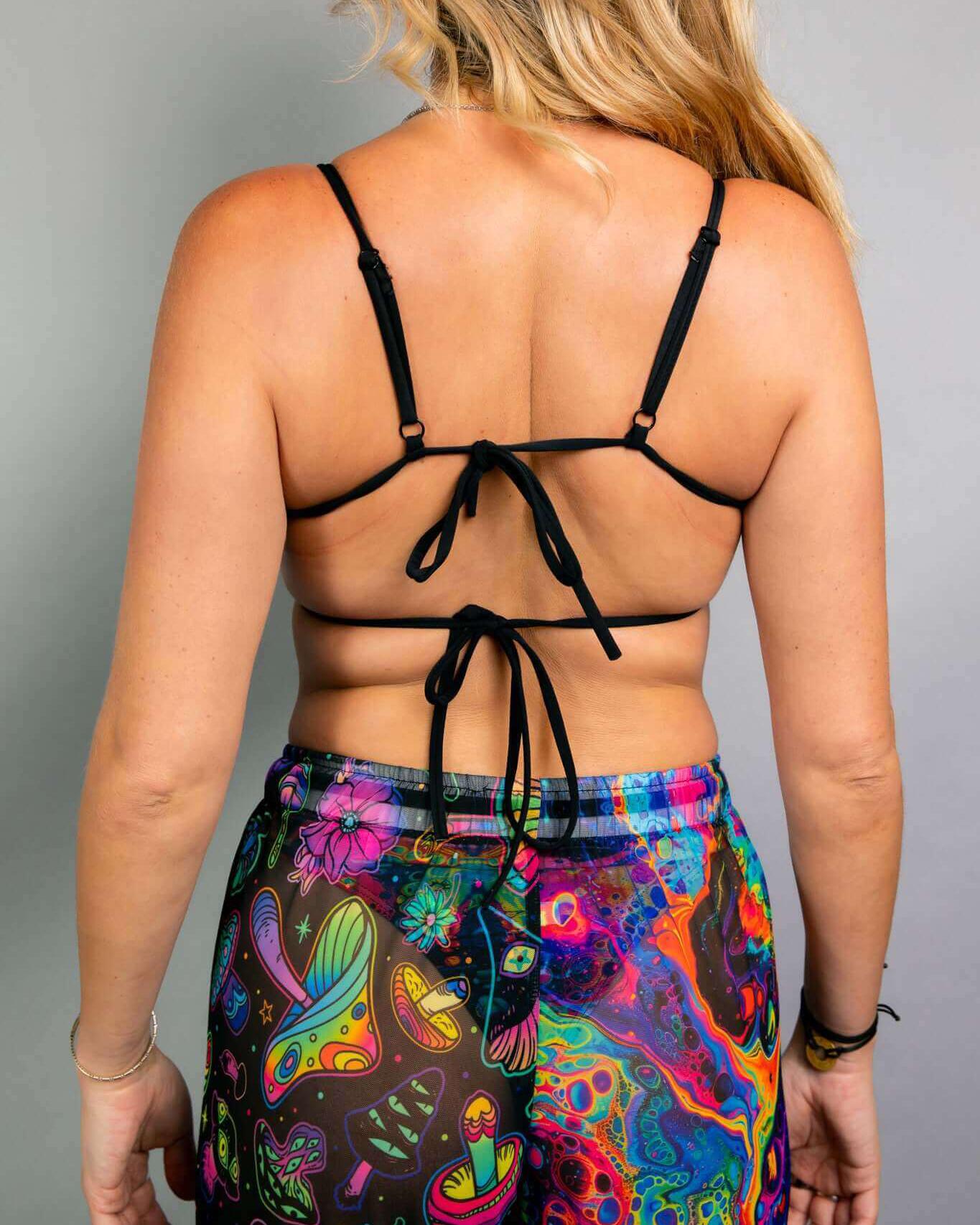 Back view of a woman in a vibrant tie strap top and colorful pants, showcasing a unique festival outfit.