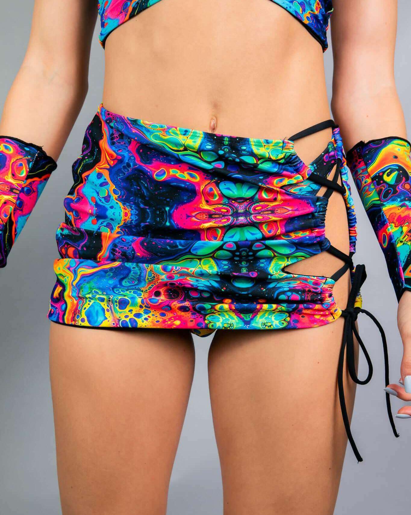 Vivid Verano Mini Skirt with rainbow trippy print and lace-up design, perfect for rave outfits.