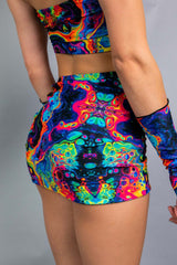 Vivid Verano Mini Skirt with vibrant rainbow trippy print, perfect for rave outfits, showcasing lace-up design.