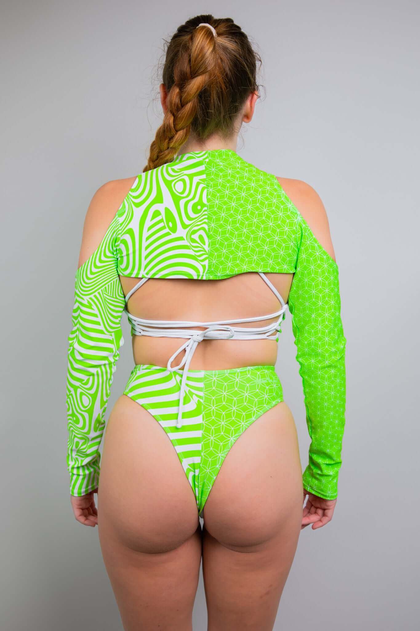  Back view of neon green and white rave outfit from Freedom Rave Wear, showcasing geometric designs, cut-out shoulders, and tie-back closure. Ideal for festivals.