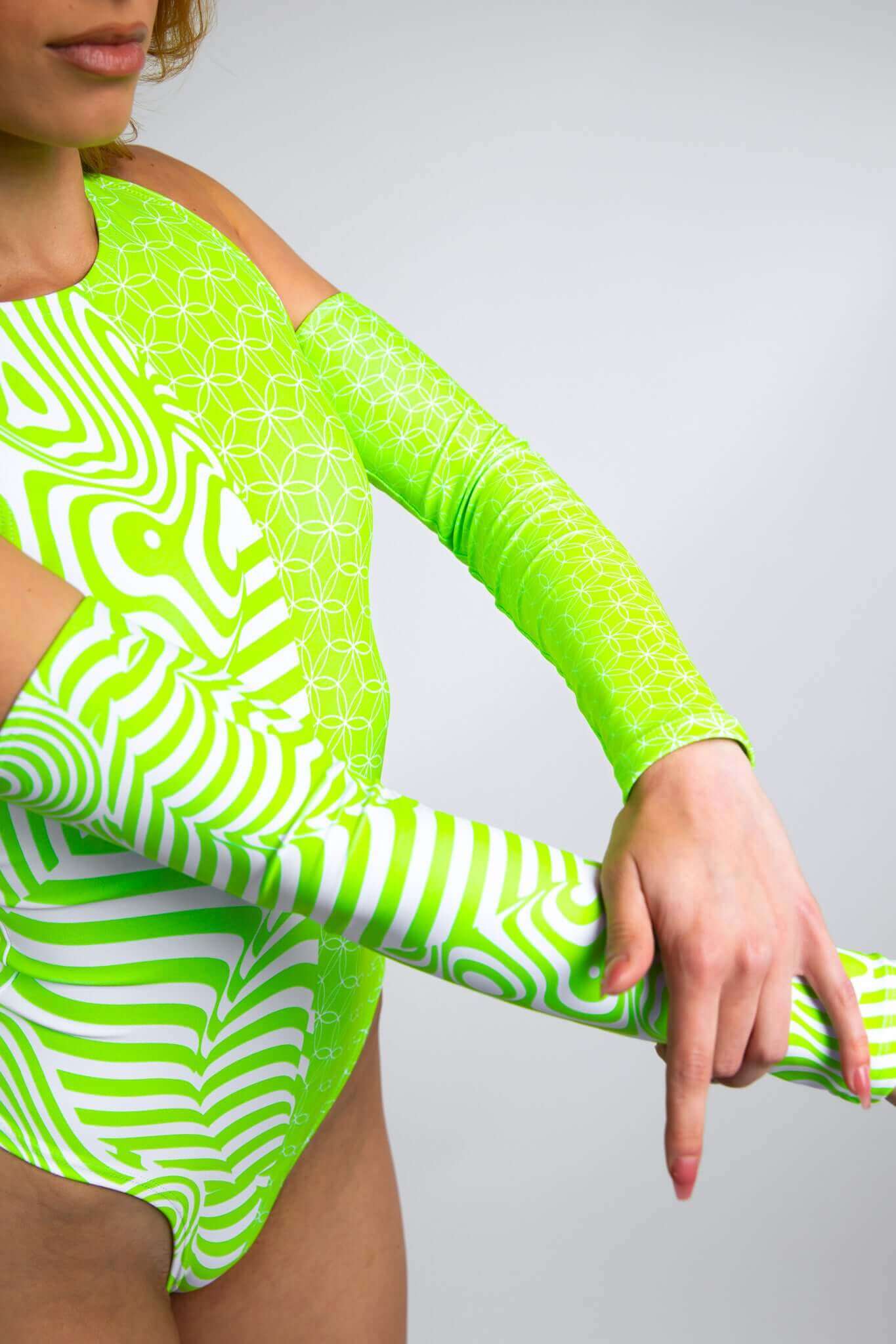 Close-up of a woman in a Freedom Rave Wear sideboob bodysuit with green and white patterns, featuring arm sleeves.