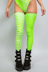 Lower body view of a woman in a Freedom Rave Wear outfit with green and white patterns, wearing thigh-high leggings and black boots.