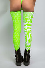 Back view of a woman in a Freedom Rave Wear outfit with green and white patterns, wearing thigh-high leggings and black boots.