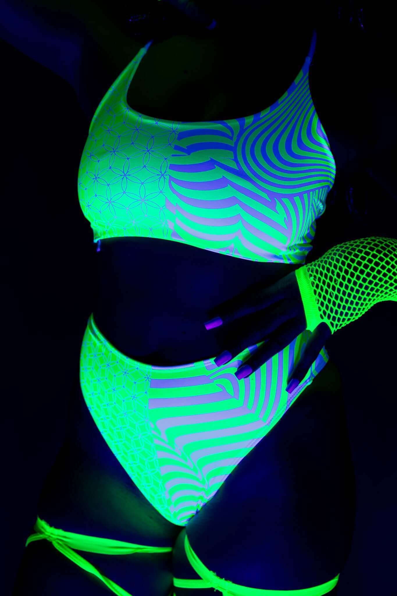 Close-up of Freedom Rave Wear outfit glowing under blacklight, with green and white psychedelic patterns and fishnet gloves.