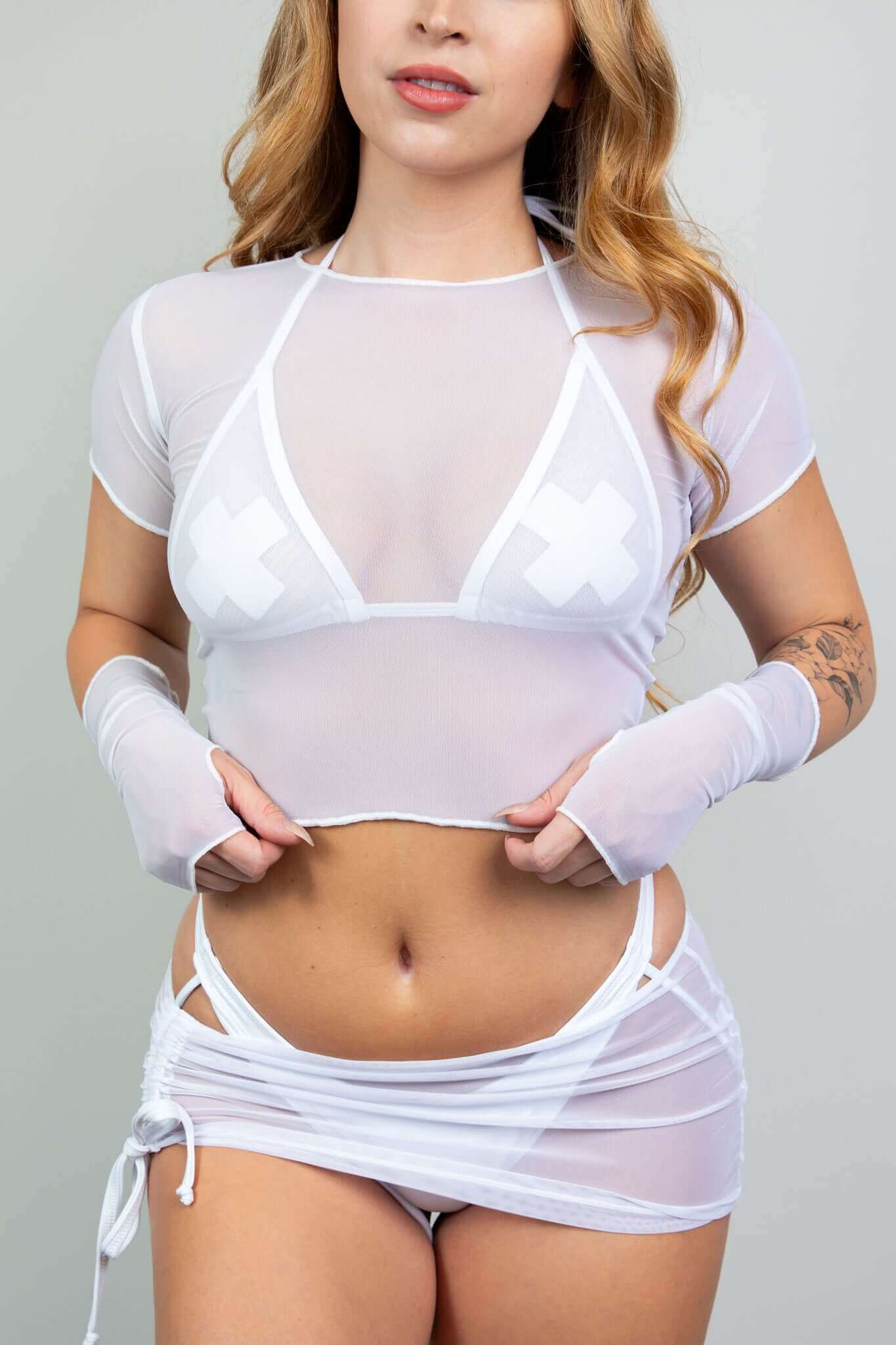 Model in sheer white rave bodysuit set from Freedom Rave Wear, featuring X pasties, arm sleeves, and side-tie mini skirt. Stylish and edgy.