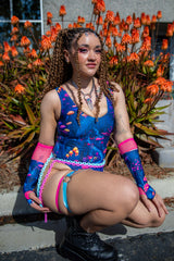 Model sitting outdoors wearing the Wildwood Classic Bodysuit, featuring an Alice in Wonderland-inspired print.