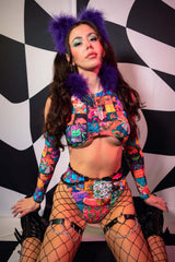 A woman poses in front of a black and white background wearing a rainbow patchwork crop top and matching bikini bottoms.