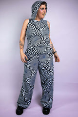A person wearing wide legged pants with a black and white geometric pattern. They have on a matching hooded tank top.