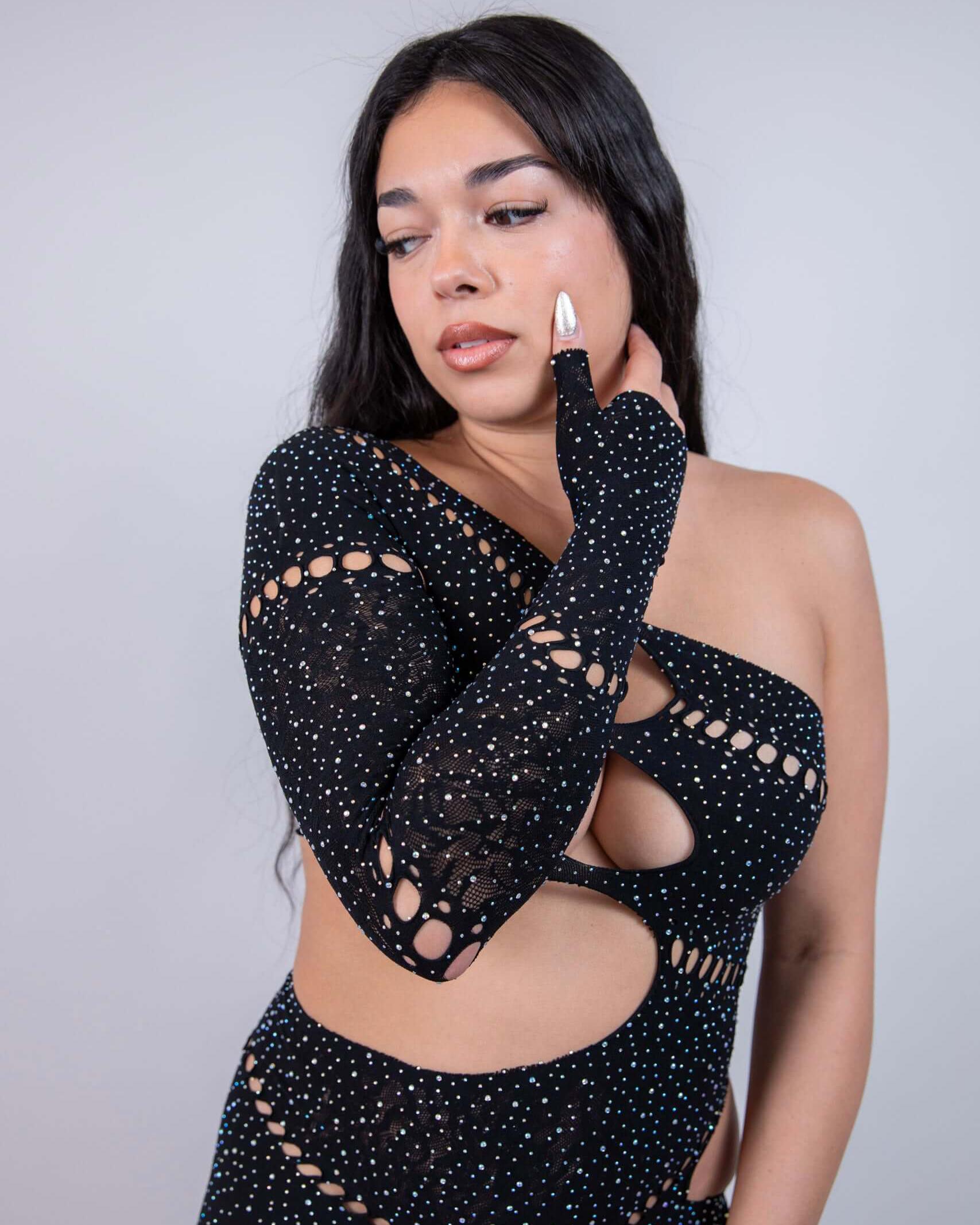 Model wearing The Zoe Asymmetrical Rhinestone Jumpsuit in black, showcasing the cutouts and sparkling rhinestone details.