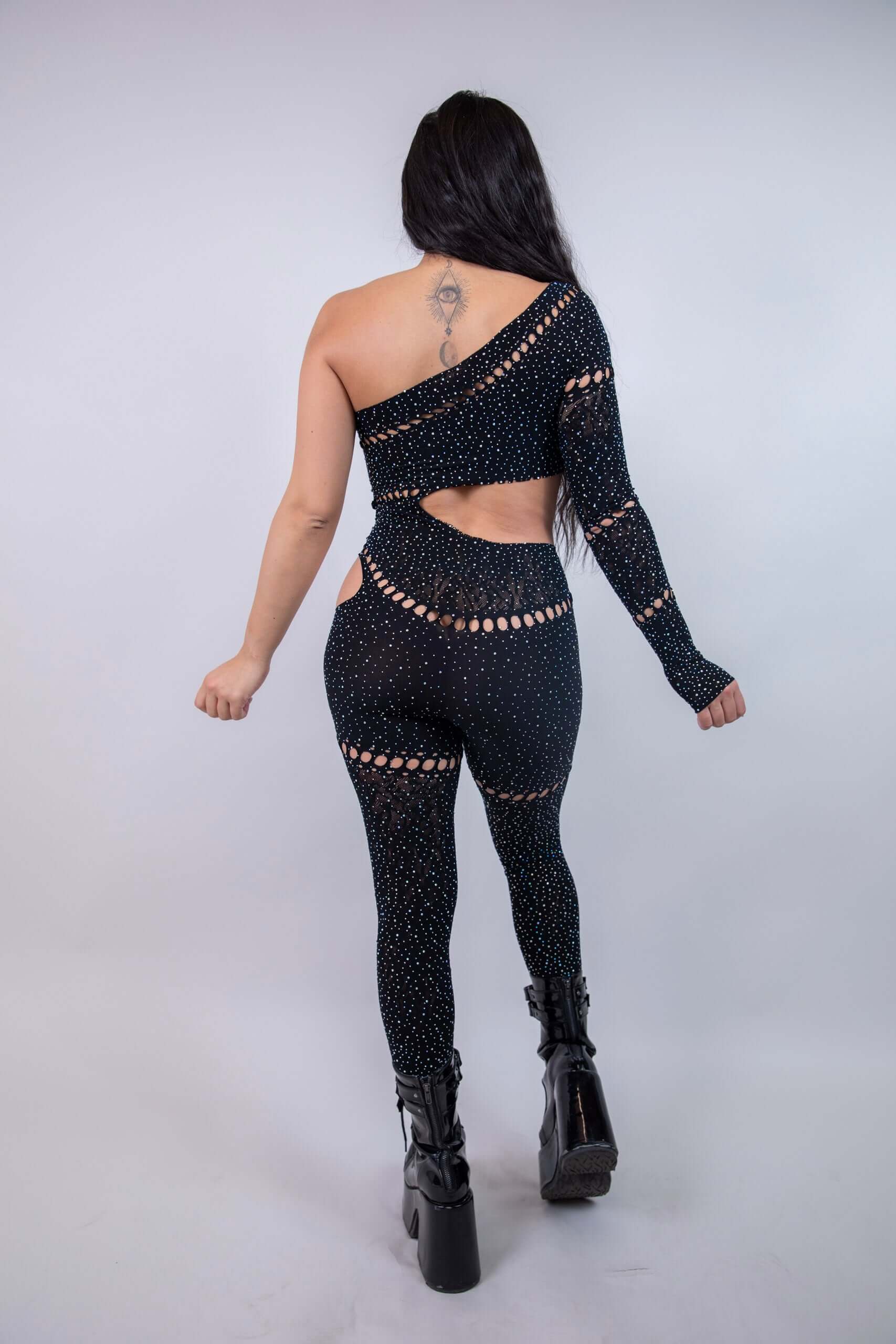 Back view of the Zoe Asymmetrical Rhinestone Jumpsuit in black, featuring cutouts and rhinestones, perfect for rave outfits.