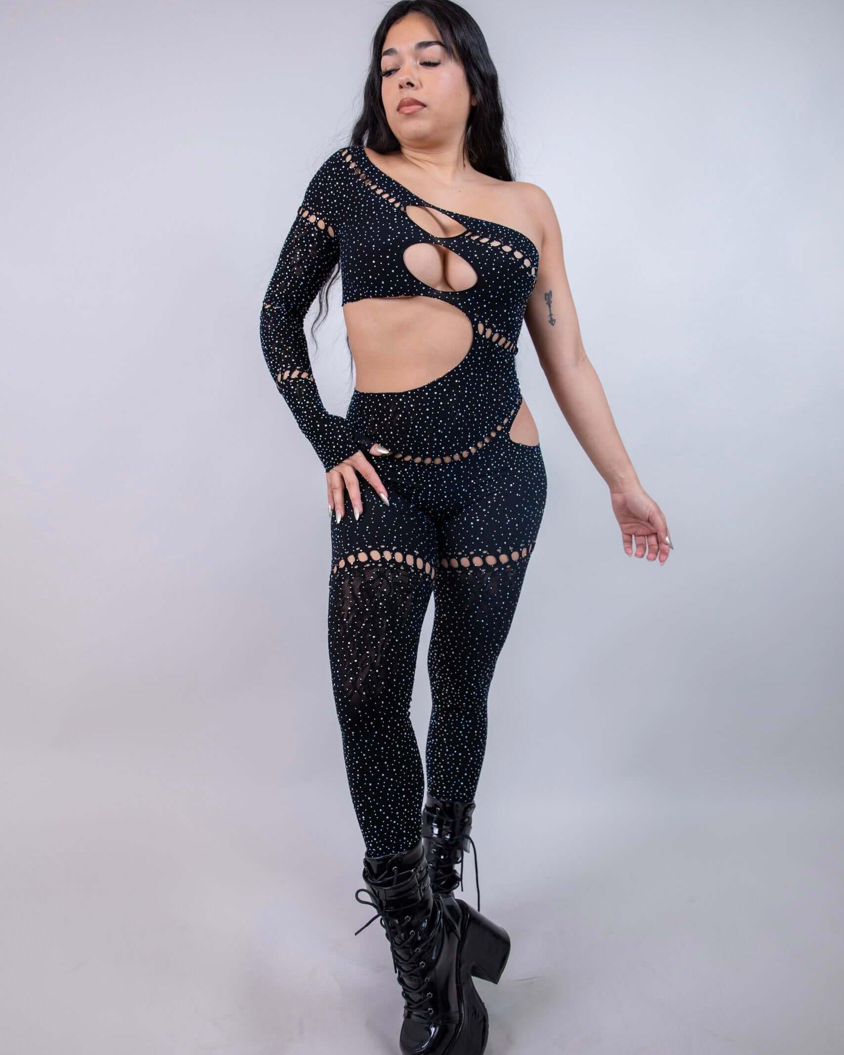 Model wearing The Zoe Asymmetrical Rhinestone Jumpsuit in black, showcasing cutouts and shimmering rhinestones, ideal for rave outfits.