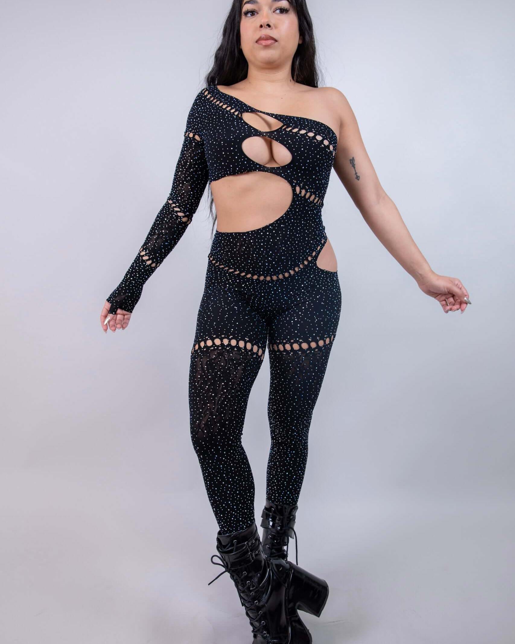 Model wearing The Zoe Asymmetrical Rhinestone Jumpsuit in black, featuring cutouts and rhinestones, perfect for rave outfits.