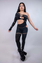 Model wearing The Zoe Asymmetrical Rhinestone Jumpsuit in black, featuring cutouts and rhinestones, perfect for rave outfits.