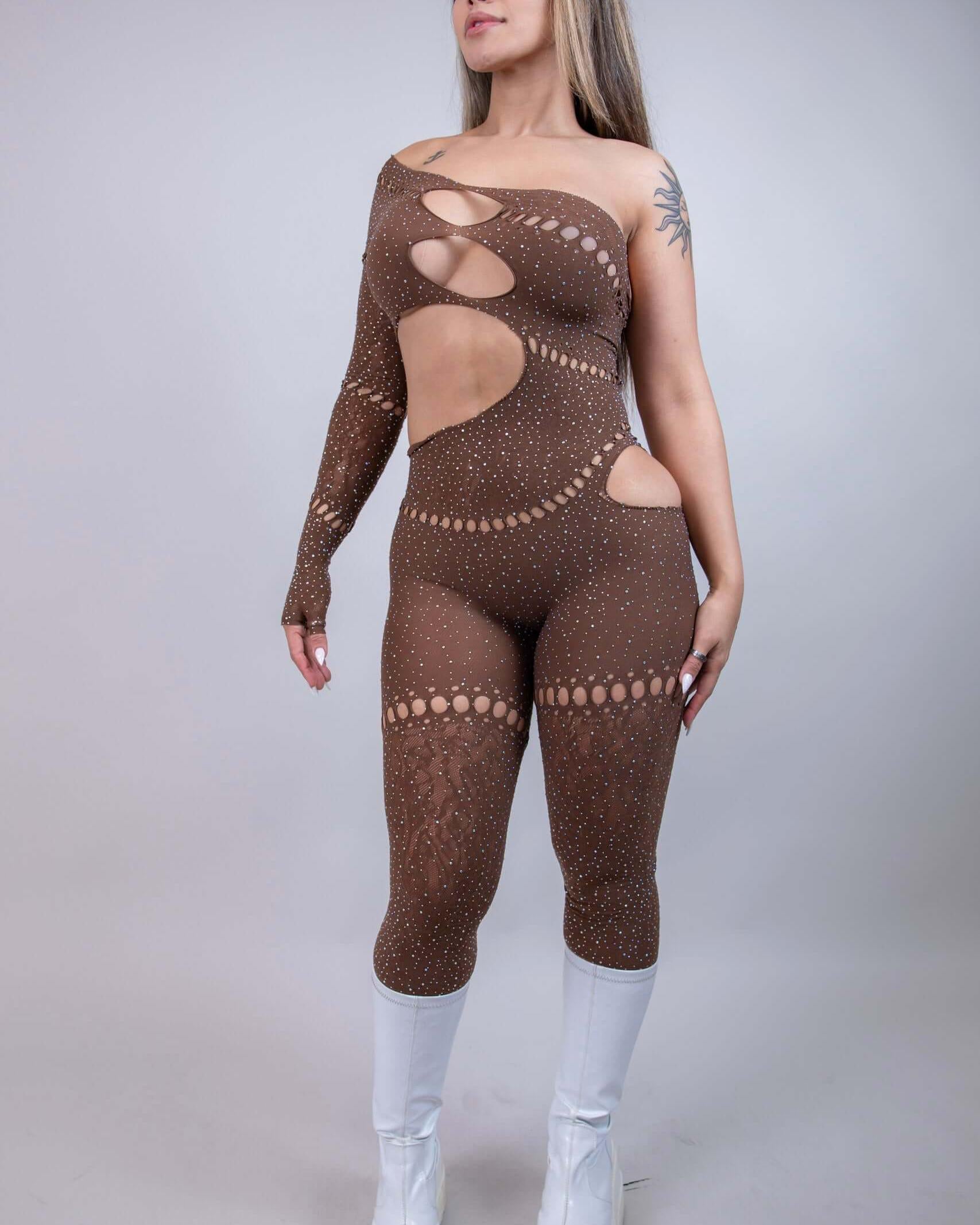 Model wearing The Zoe Asymmetrical Rhinestone Jumpsuit in brown, showcasing cutouts and rhinestones, perfect for rave outfits.