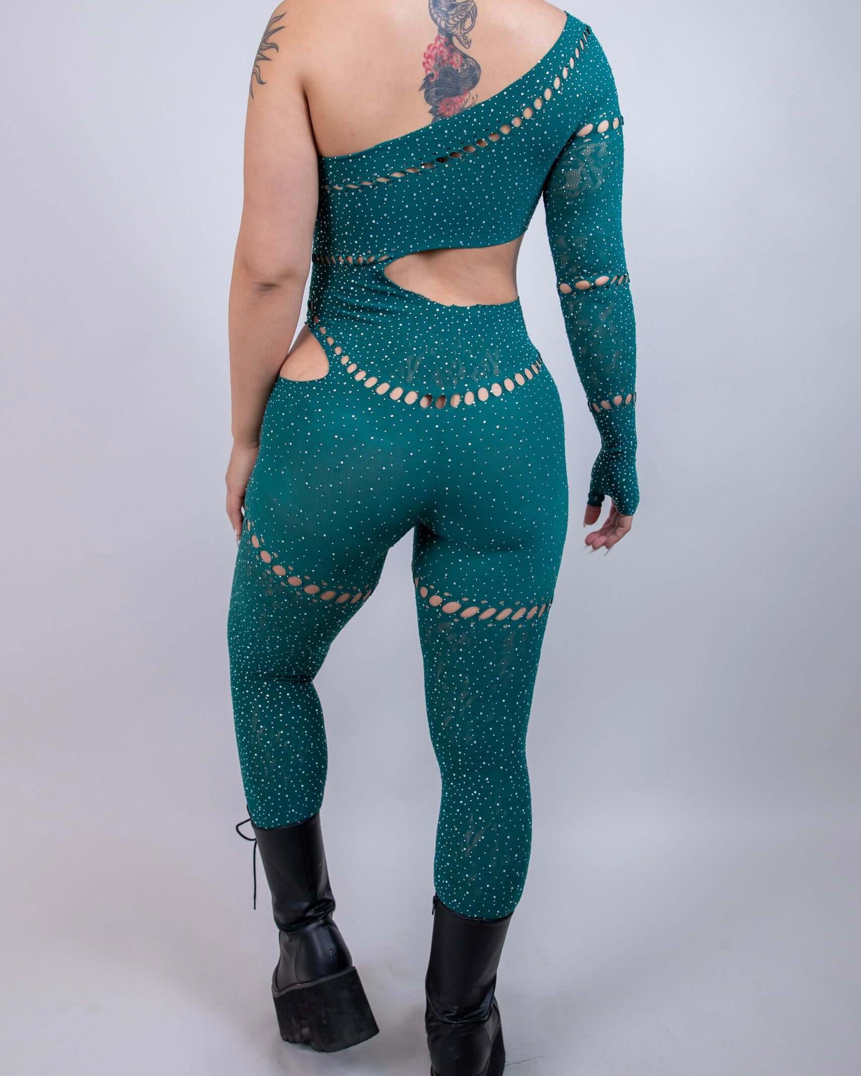 Model showcasing the back of The Zoe Asymmetrical Rhinestone Jumpsuit in emerald, featuring cutouts and rhinestones.