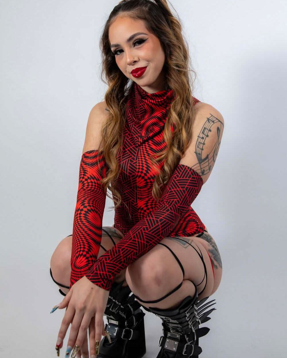 Model showcasing Amplitude Arm Sleeves in red and black, styled with rave outfits and trendy accessories.