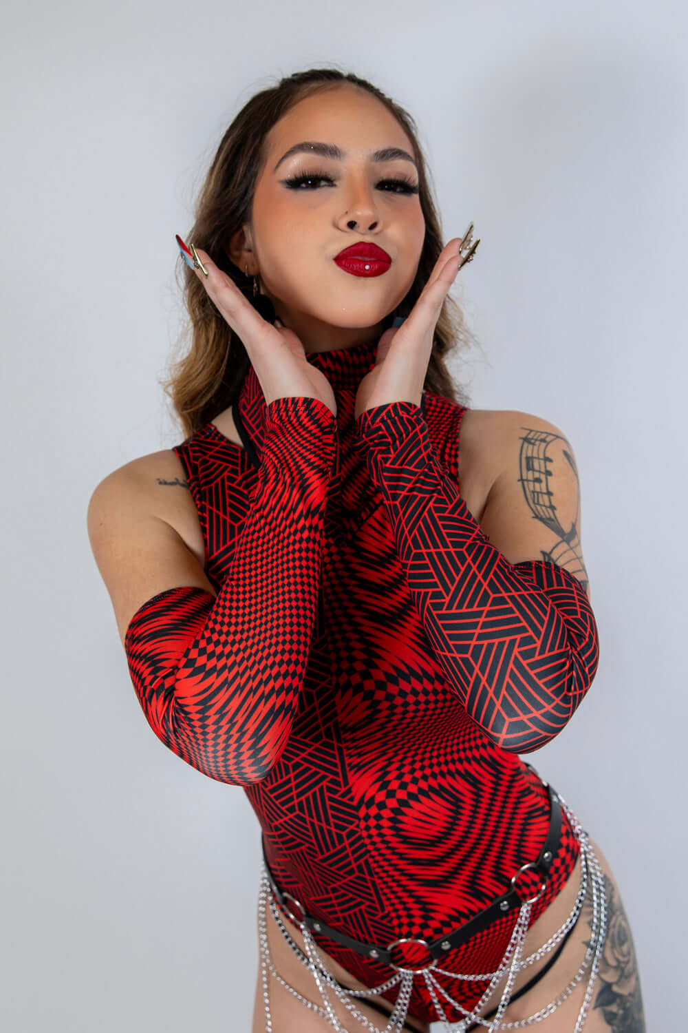 Model showcasing Amplitude Arm Sleeves in red and black, styled for rave outfits, combining fashion and performance.