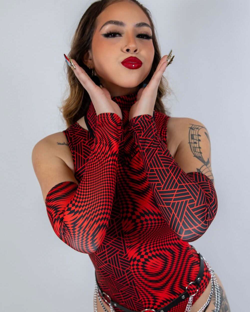 Model showcasing Amplitude Arm Sleeves in red and black, styled for rave outfits, combining fashion and performance.