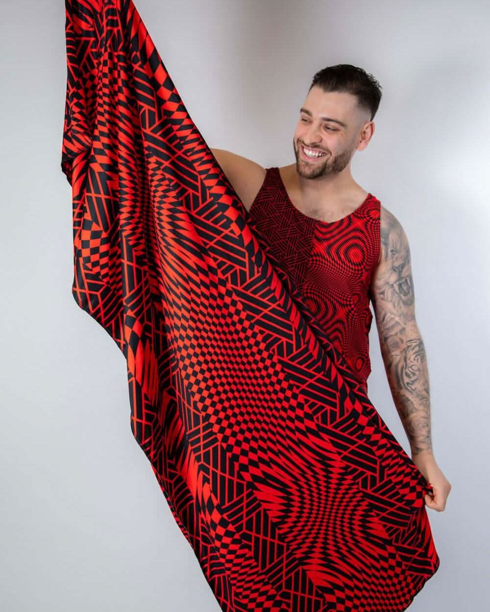 Man showcasing the Amplitude Festival Scarf with red and black geometric patterns, perfect for rave outfits.