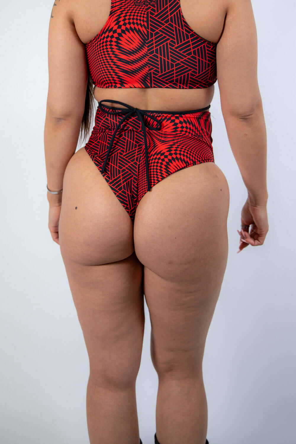 Back view of Amplitude High Waisted Bikini Bottoms featuring a red and black abstract design, perfect for rave outfits.