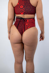 Back view of Amplitude High Waisted Bikini Bottoms featuring a red and black abstract design, perfect for rave outfits.