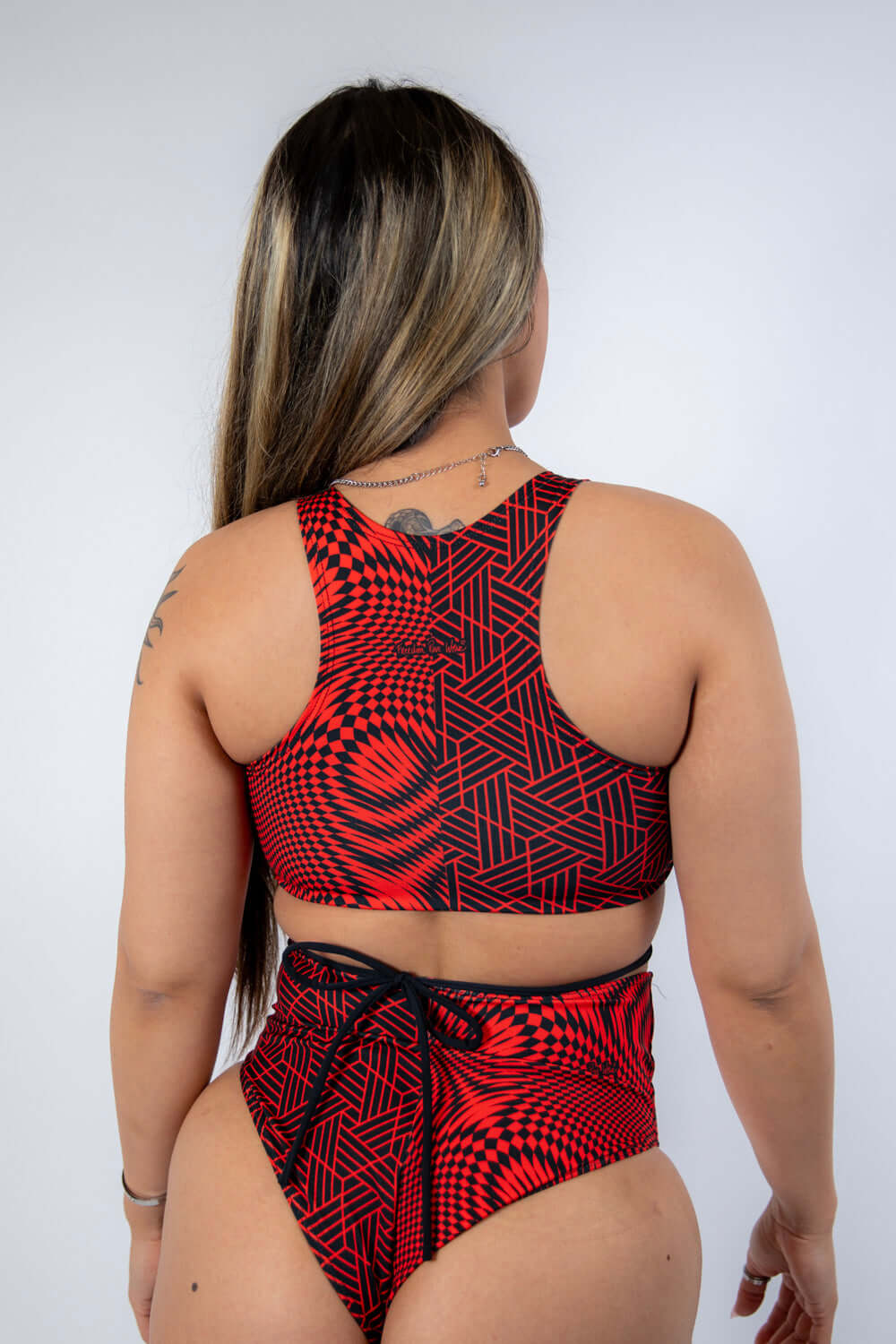 Model wearing Amplitude Teaser Top with strappy back, showcasing a trendy red abstract rave outfit.