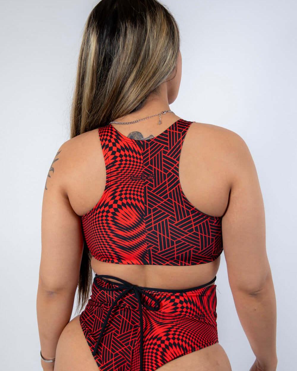 Model wearing Amplitude Teaser Top with strappy back, showcasing a trendy red abstract rave outfit.