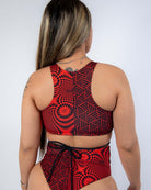 Model wearing Amplitude Teaser Top with strappy back, showcasing a trendy red abstract rave outfit.