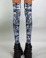 Archaic Leg Sleeves in black and white pattern, perfect for rave outfits, showcasing over-the-knee fit and stylish boots.