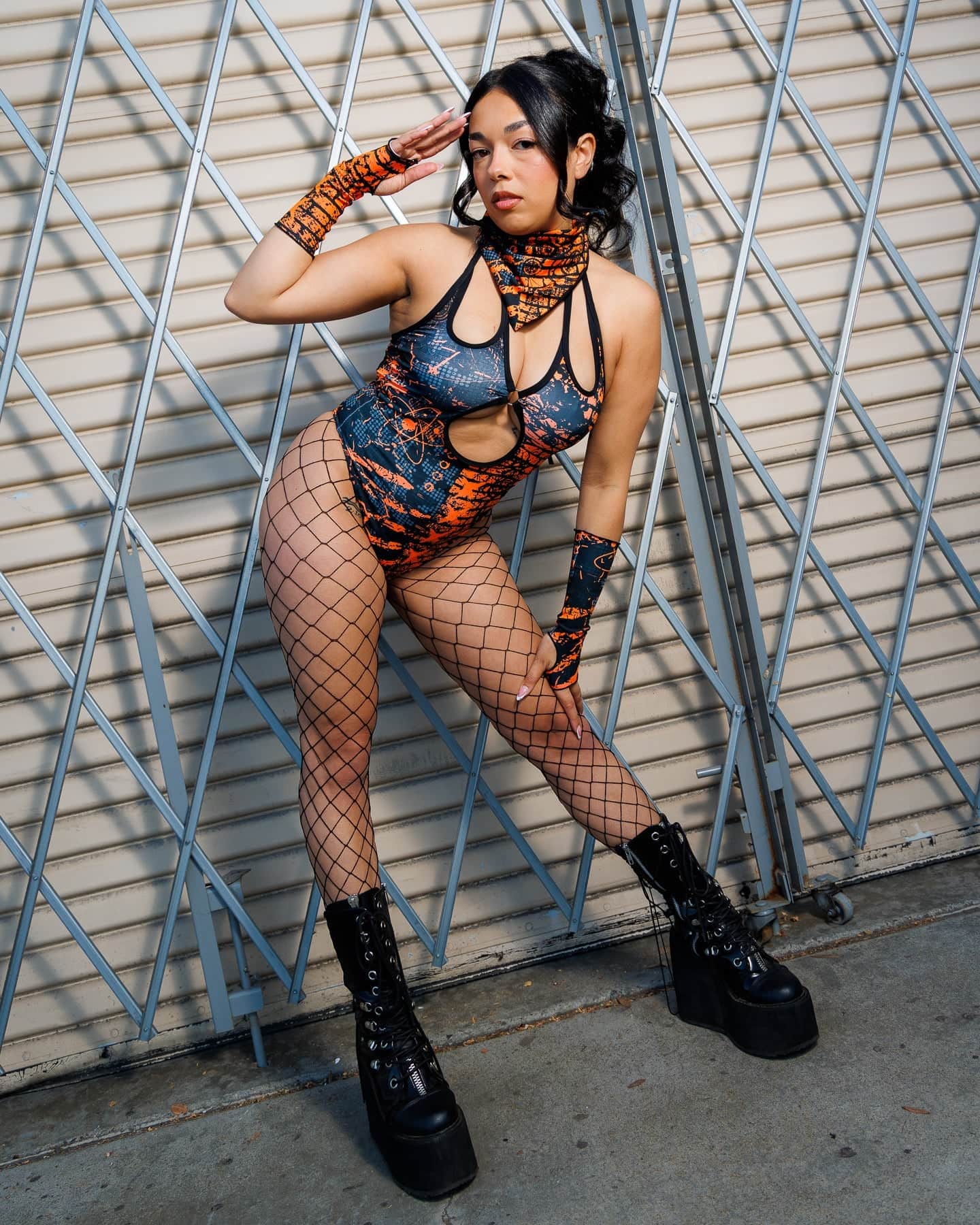 Model wearing the Atomic Bandana in festival attire with orange and black tones, showcasing its edgy dystopian style against a metal backdrop.