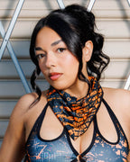 Model wearing Atomic Bandana in bold orange and black tones, styled as a neck scarf for a post-apocalyptic festival look.