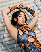 Model wearing Atomic Gloves, featuring flame-meets-galaxy print, in a stylish pose against a geometric background.