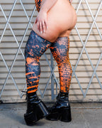 Atomic Leg Sleeves with vibrant orange and black pattern paired with platform boots in a bold fashion look.