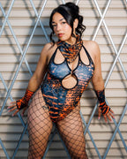 Model wearing Atomic Cross Faded Bodysuit with bold black and orange print, posing confidently against a metallic backdrop.
