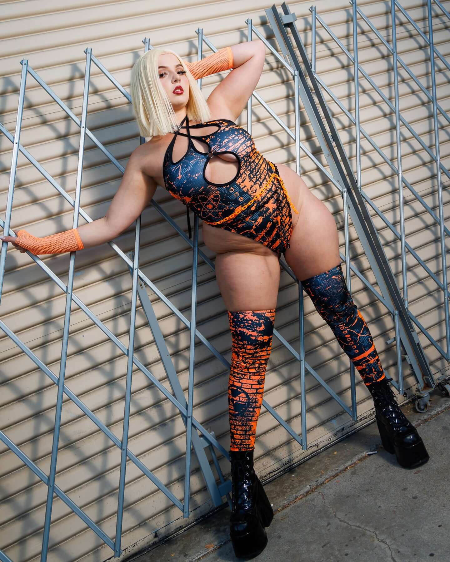Model wearing Atomic Leg Sleeves with vibrant patterns standing against a metal gate, showcasing bold, high-energy vibes and eye-catching details.