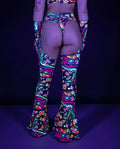 Awaken Bell Chaps from the back, featuring a vibrant psychedelic pattern with mushrooms and eyes, perfect for a rave festival. — uv