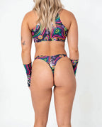 Awaken Risk Bottoms front view, featuring a model in black high-cut rave bottoms with a vibrant psychedelic mushroom and eye pattern, perfect for festivals. — cyc_2