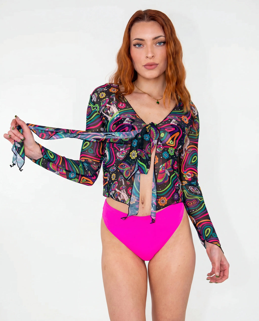 Awaken Sea Fairy Tie Top shown from the front on a model, featuring a sheer, long-sleeved, psychedelic multi-color rave top over a pink bodysuit. — cyc_5