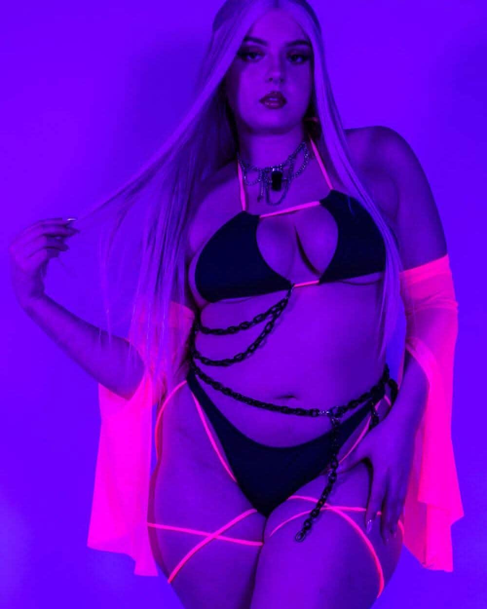 Neon-lit pose of the Black and Hot Pink Strappy Bikini Top, glowing under blacklight for a bold rave look.