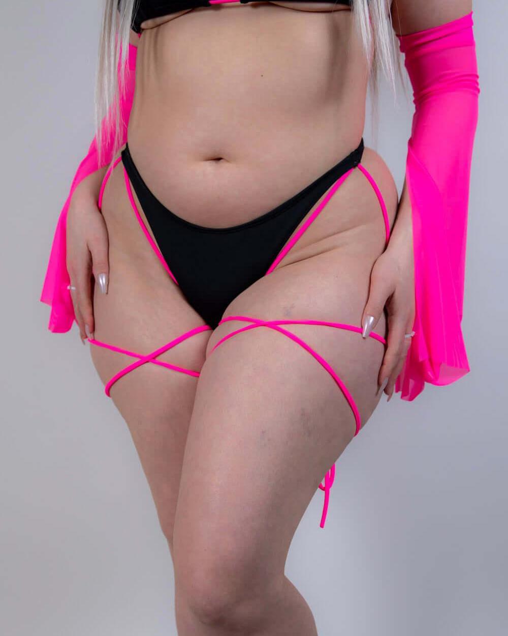 Angled pose in the Black and Hot Pink Strappy High Hip Bottoms, highlighting the strappy waistband and sleek fit.