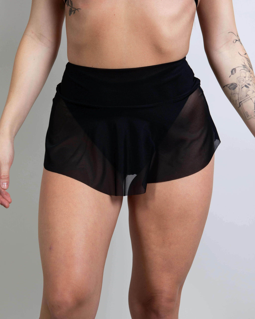 Black mesh micro skater skirt showcasing playful design, ideal for rave outfits and dancing at events.