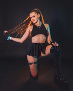 Model wearing black mesh swirl rave skirt with crop top at festival with neon lighting
