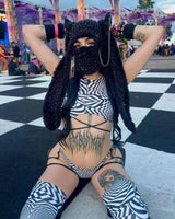 Woman in a rave festival outfit with black and white geometric patterns, bedazzled cat mask and rave accessories,