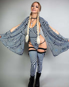 Woman in black and white patterned outfit striking a pose, showcasing a stylish rave look with bold accessories.