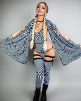 Woman in black and white patterned outfit striking a pose, showcasing a stylish rave look with bold accessories.
