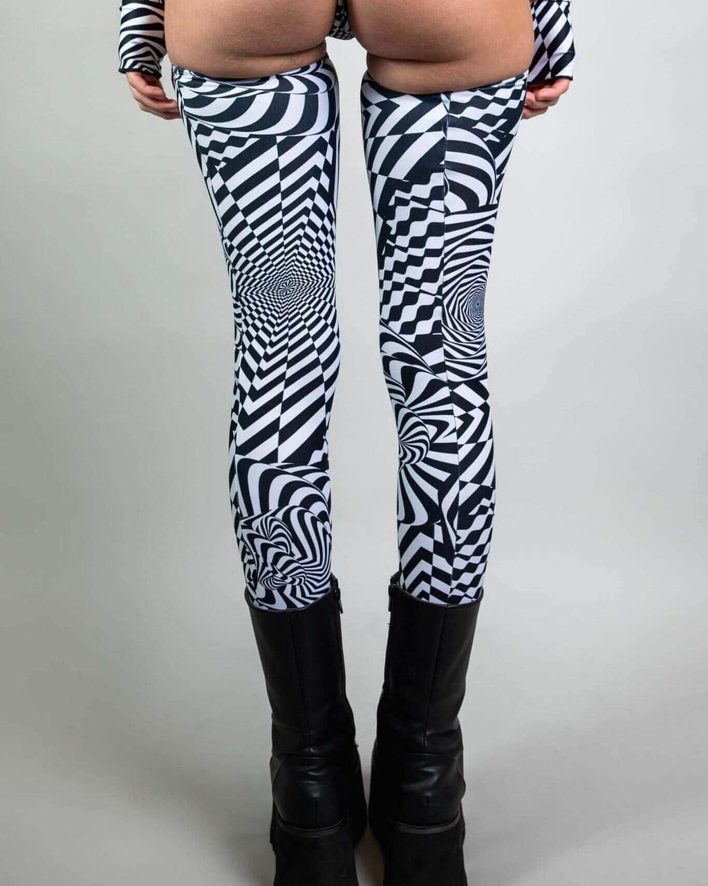 Distortion Leg Sleeves featuring abstract optical patterns, perfect for rave outfits, worn with stylish black platform boots.