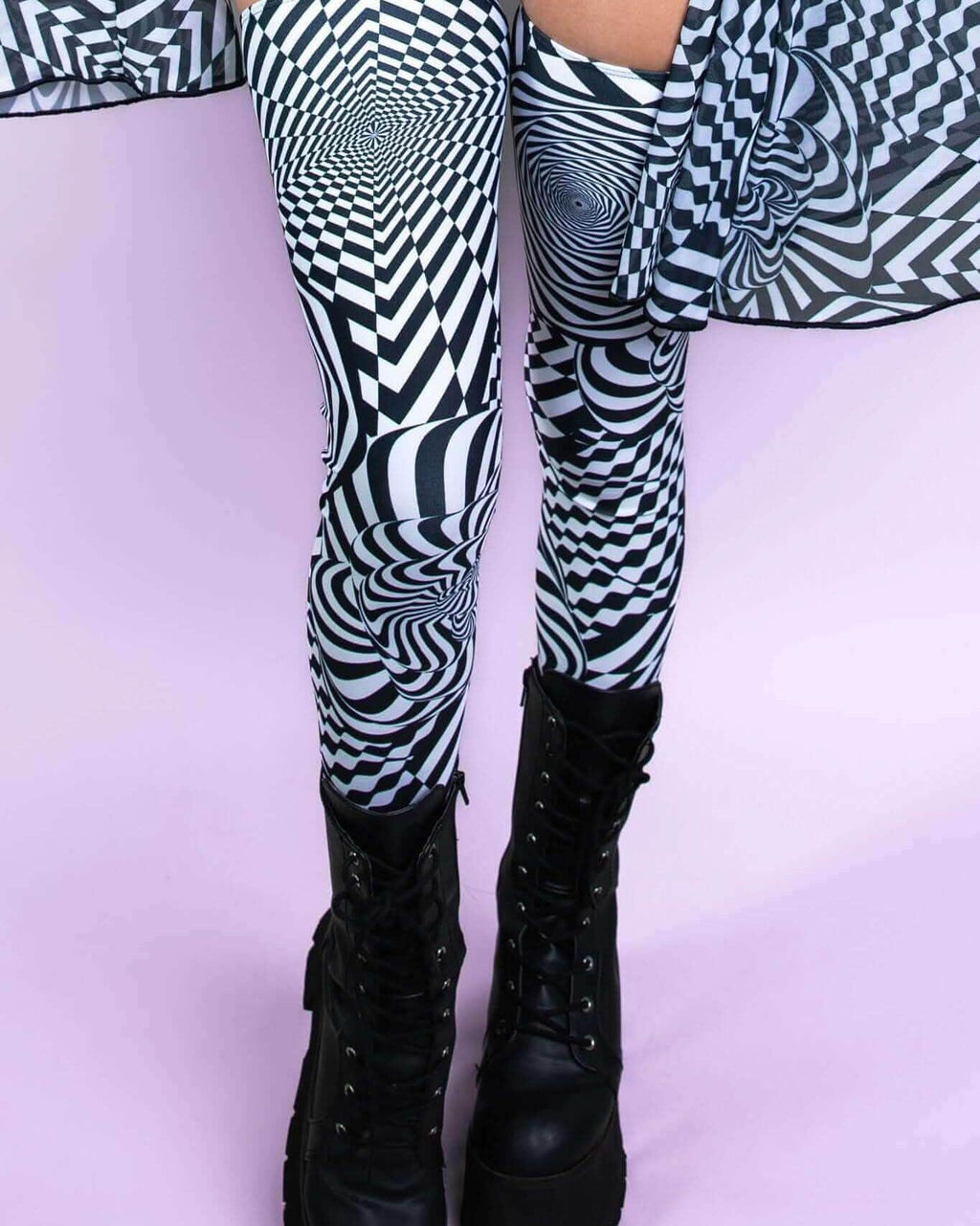 Distortion Leg Sleeves with abstract optical design, paired with black combat boots, perfect for rave outfits.