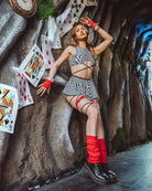 Model wearing a striped wrap skirt and top against a colorful backdrop of playing cards, perfect for rave outfits.
