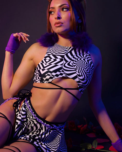 Distortion rave top with geometric black white pattern and strappy underboob design modeled against purple background
